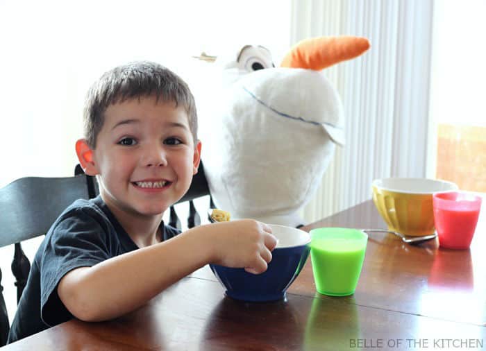 A little boy sitting at a table net to a stuffed snowman