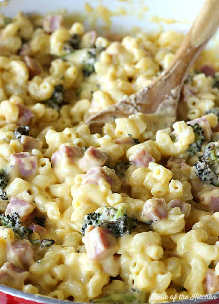 A bowl of macaroni and cheese with a wooden spoon