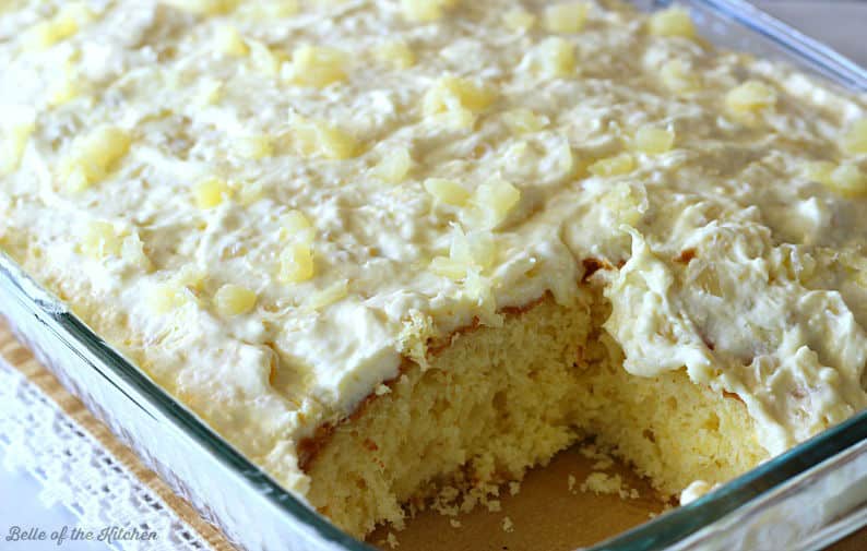 a baking dish full of pineapple cake with a slice taken out