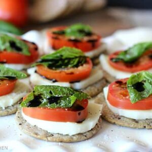 crackers topped with sliced tomato, mozzarella, basil, and balsamic glaze