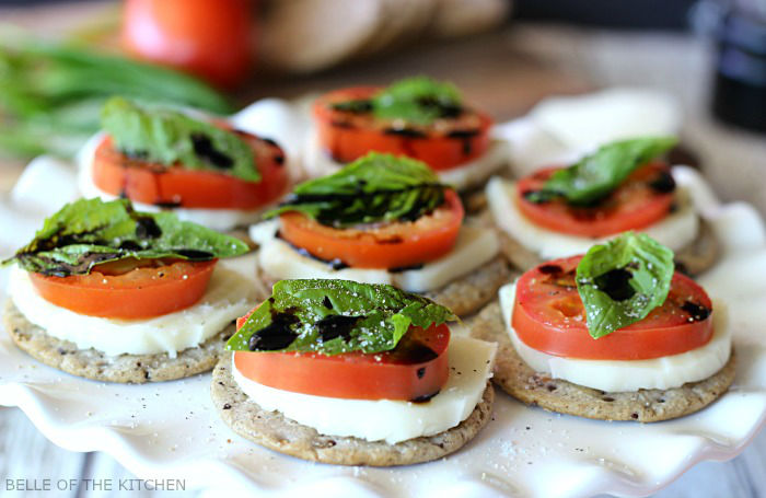 crackers topped with sliced tomato, mozzarella, basil, and balsamic glaze
