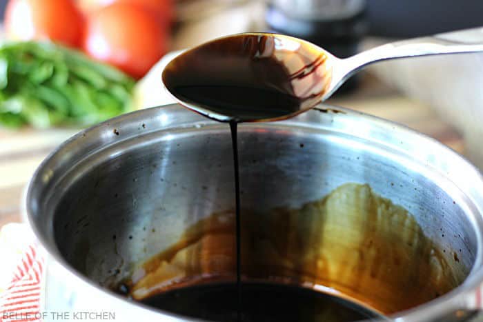 a spoon dipping into a pot of balsamic glaze