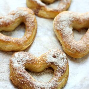 soft pretzels in the shape of hearts on a sheet pan topped with sugar