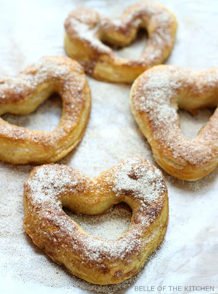 soft pretzels in the shape of hearts on a sheet pan topped with sugar