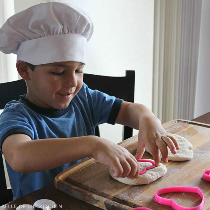 a boy cutting shapes from dough with a cookie cutter