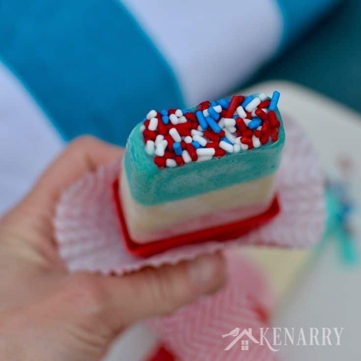 A close up of a person holding a popsicle with sprinkles