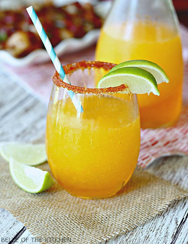 A close up of a margarita in a glass with lime wedges