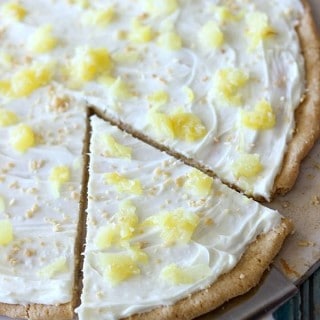 This Pina Colada Fruit Pizza is the perfect summer time treat! Made with a sugar cookie crust, a pineapple cream cheese frosting, and topped with juicy pineapple, you're going to want this all year round!