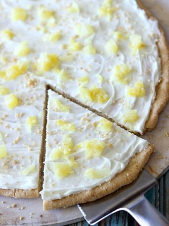 A piece of fruit pizza topped with pineapple