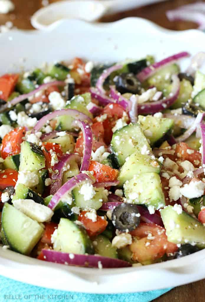 A plate full of tomatoes, cucumbers, red onion, black olives, and feta cheese