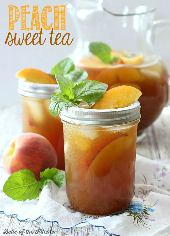A close up of a glass of peach tea filled with mint and peach slices
