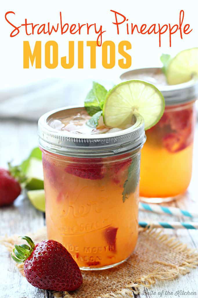 A close up of mason jars filled with strawberry mojitos, fresh strawberries, mint, and lime slices on the rim