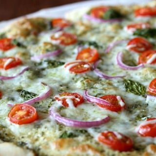 This Caprese Pizza is made with pesto, tomatoes, red onions, and fresh basil, then topped with mozzarella and a drizzle of balsamic reduction at the end!