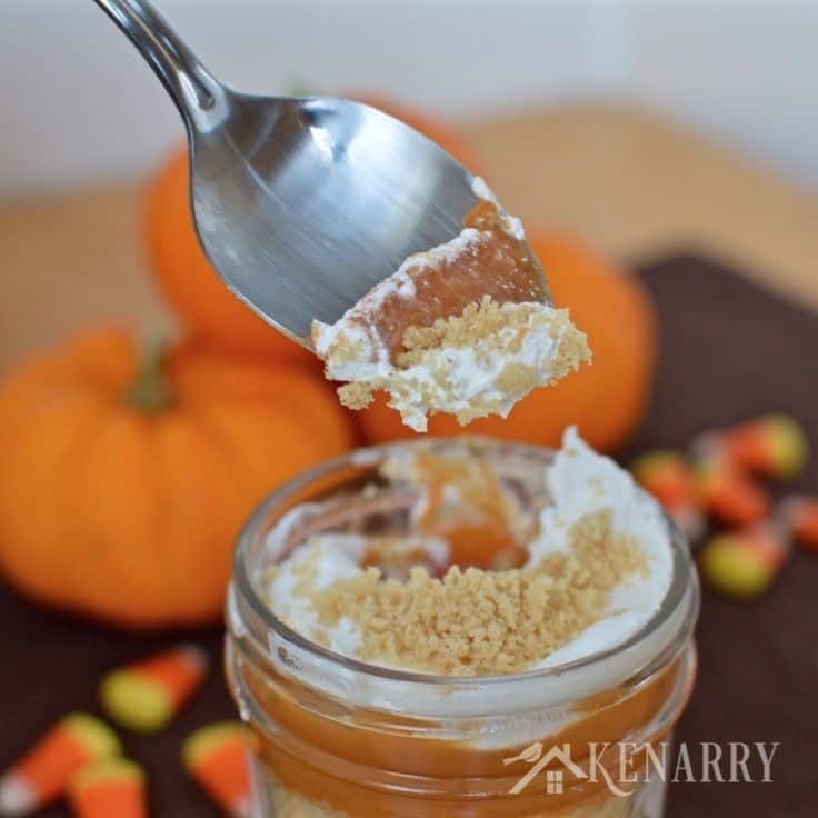 jars with layers of pumpkin, cream cheese, and graham cracker crumbs with a spoon digging in