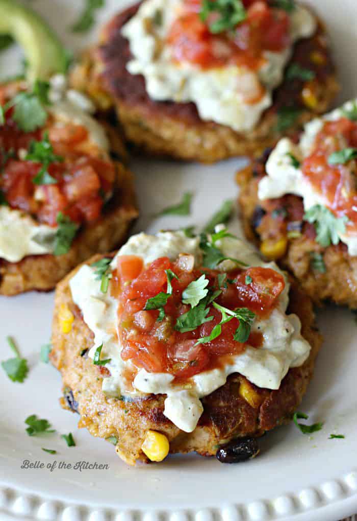 A plate full of tuna cakes topped with salsa, cilantro