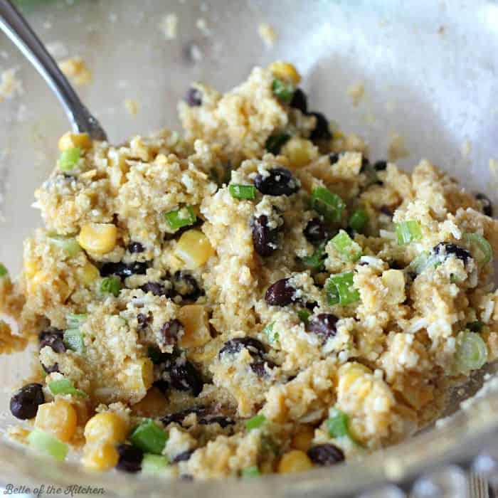 A close up of a bowl of tuna mixed with black beans, corn, and green onions