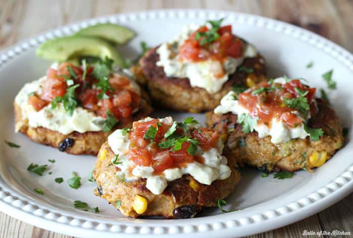 A plate full of tuna cakes topped with salsa, cilantro, and avocado