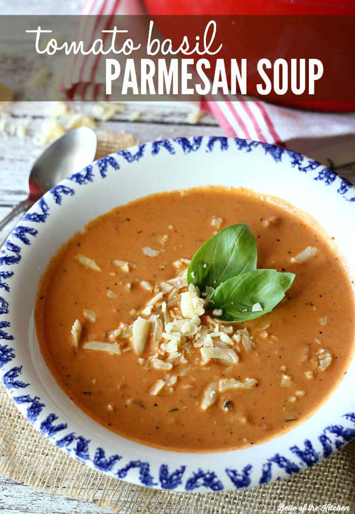 A bowl of tomato soup topped with shredded cheese and basil