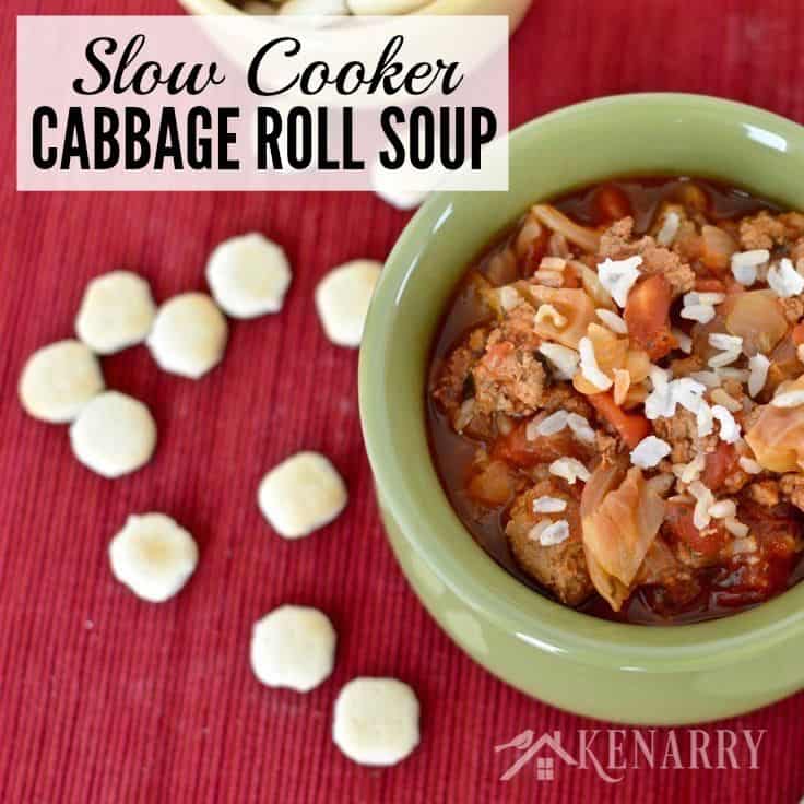 A green bowl of cabbage soup with crackers on the side