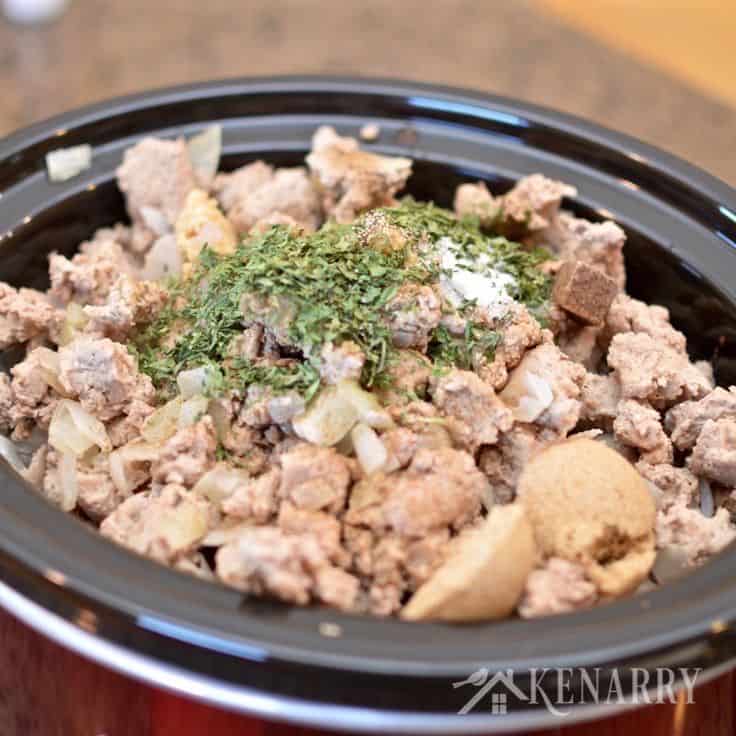 A crockpot filled with rice meat and vegetables, topped with spices