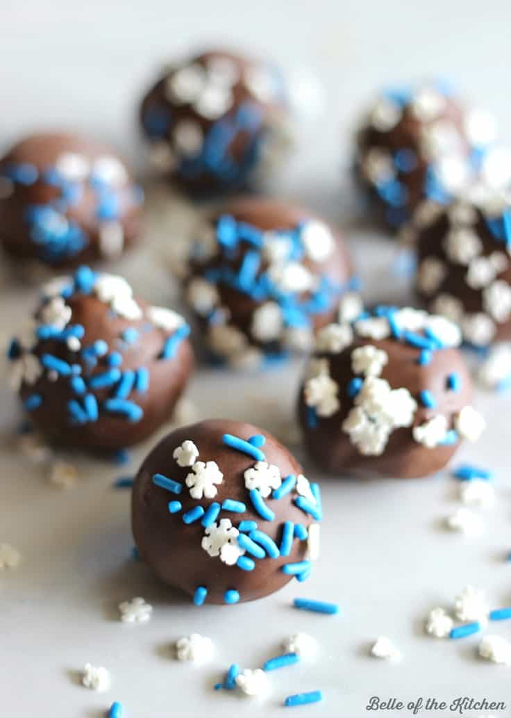 A close up of chocolate cake balls with blue and white sprinkles