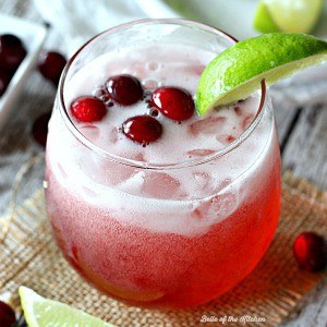 A glass of limeade with cranberries and a lime slice