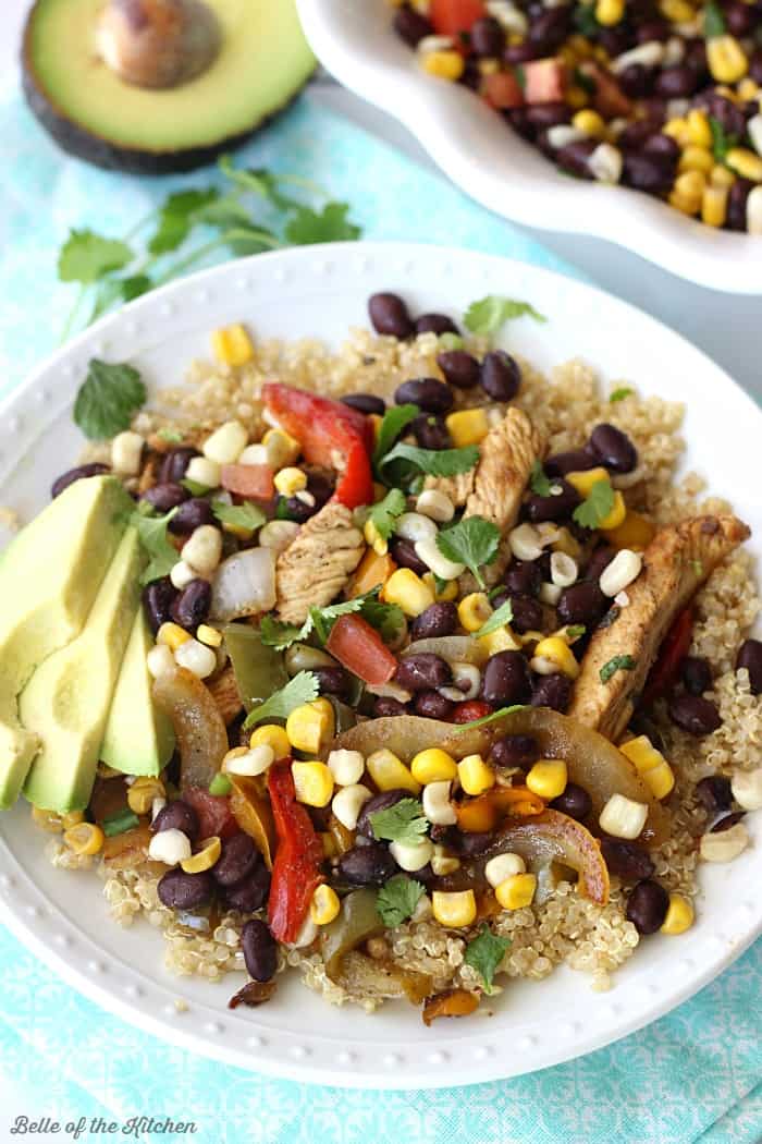 A plate full of food, with chicken, vegetables, and avocado