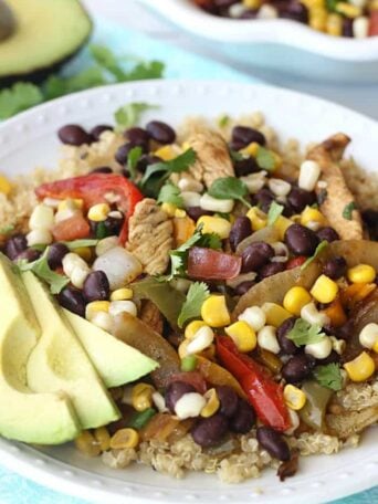 A plate full of food, with Chicken, Quinoa, avocado, black beans, onions, corn, and peppers