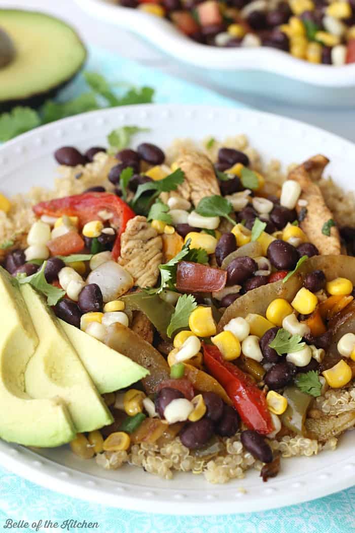 A plate full of food, with Chicken, Quinoa, avocado, black beans, onions, corn, and peppers