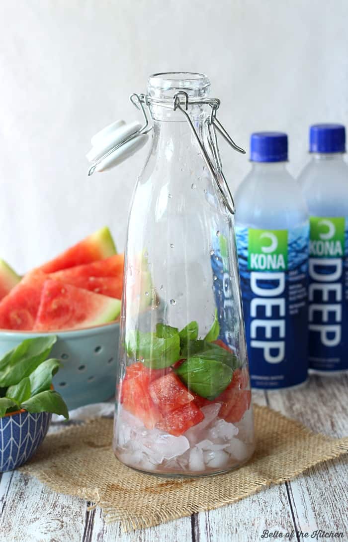 A close up of a carafe filled with watermelon, basil, and water