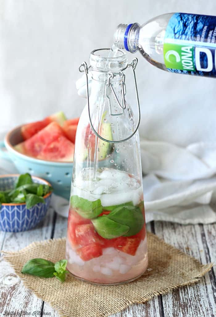 A close up of a carafe filled with watermelon, basil and water