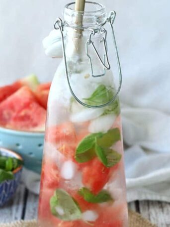 A close up of a carafe filled with watermelon, basil and water