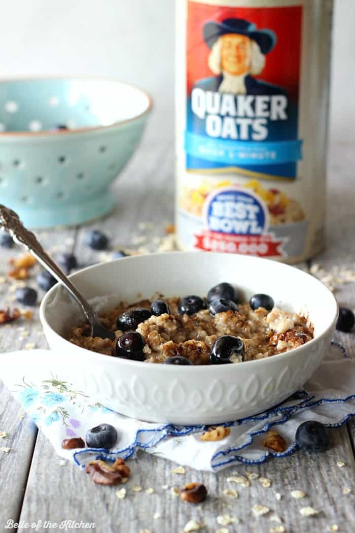 A bowl of oatmeal filled with blueberries with a can of oats in the background