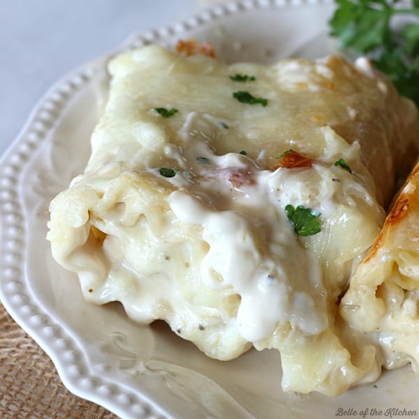 A close up of a lasagna roll with Alfredo sauce