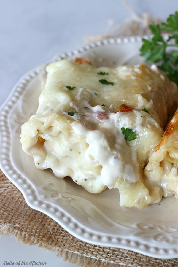 A close up of a lasagna roll with Alfredo sauce