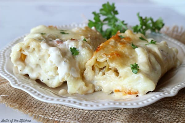 A close up of a lasagna roll with Alfredo sauce