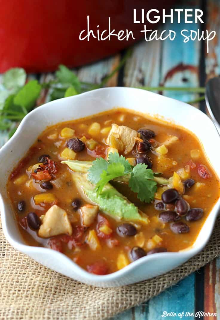 A bowl of chicken taco soup with a sprig of cilantro and avocado