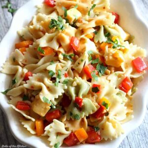 A close up of a bowl of pasta salad with cheese and chopped peppers