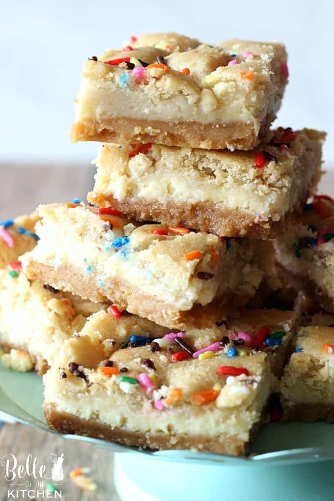 a plate of cheesecake bars stacked up with sprinkles on top