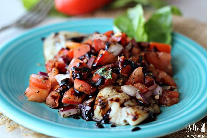 A blue plate topped with tilapia and bruschetta