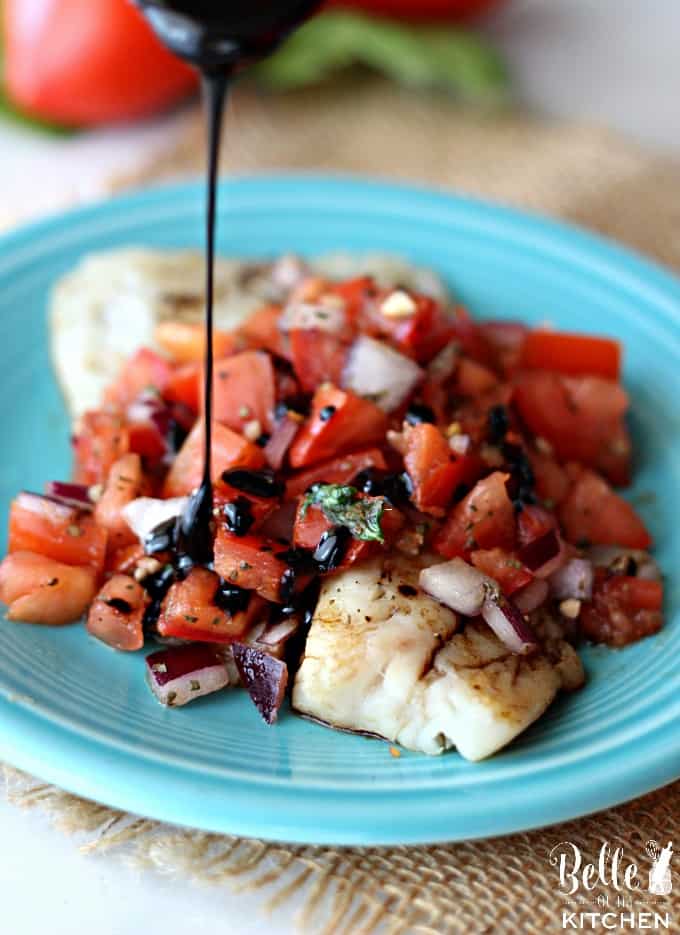 A blue plate topped with tilapia and bruschetta