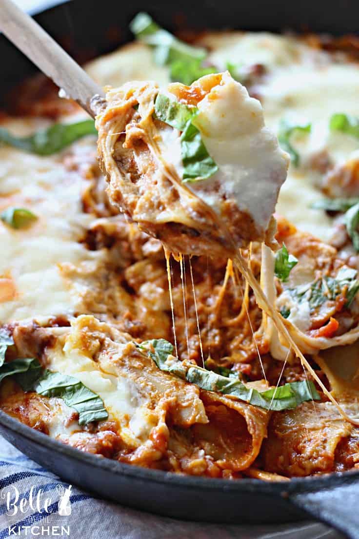 A close up of a pan of lasagna with a spoon pulling some out