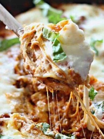A close up lasagna with cheese being pulled out of a skillet
