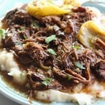 A plate of Mississippi pot roast on top of mashed potatoes