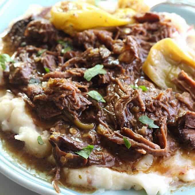 A plate of Mississippi pot roast on top of mashed potatoes 