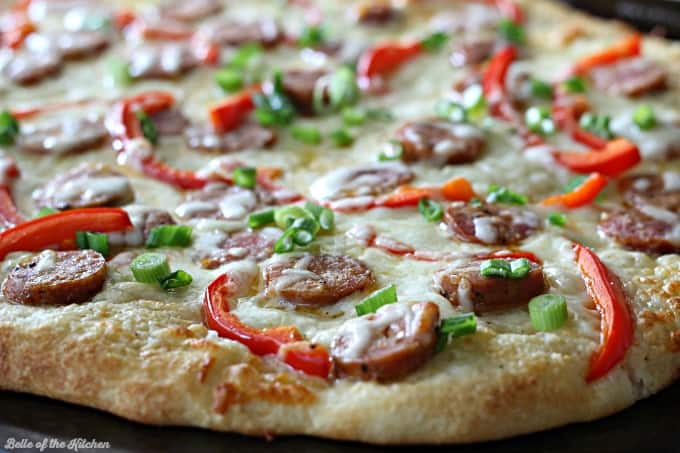 A pizza covered in cheese, sausage, peppers, and green onions