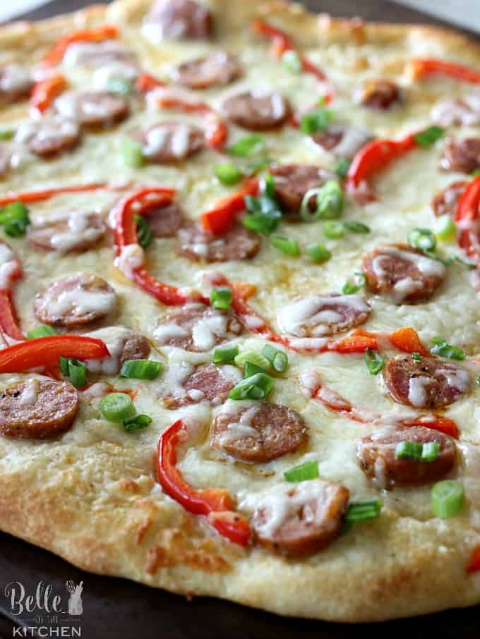 A pizza covered in cheese, sausage, peppers, and green onions