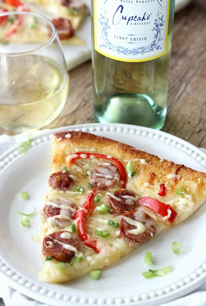 A slice of pizza on a plate beside a bottle of wine