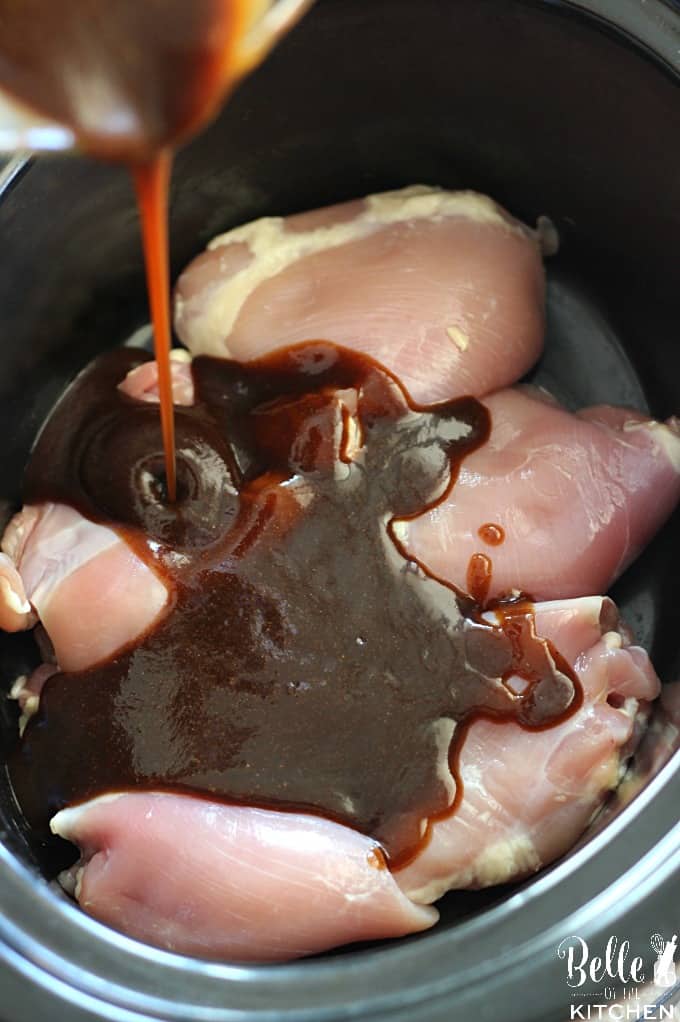 a crockpot filled with chicken thighs and sauce poured on top