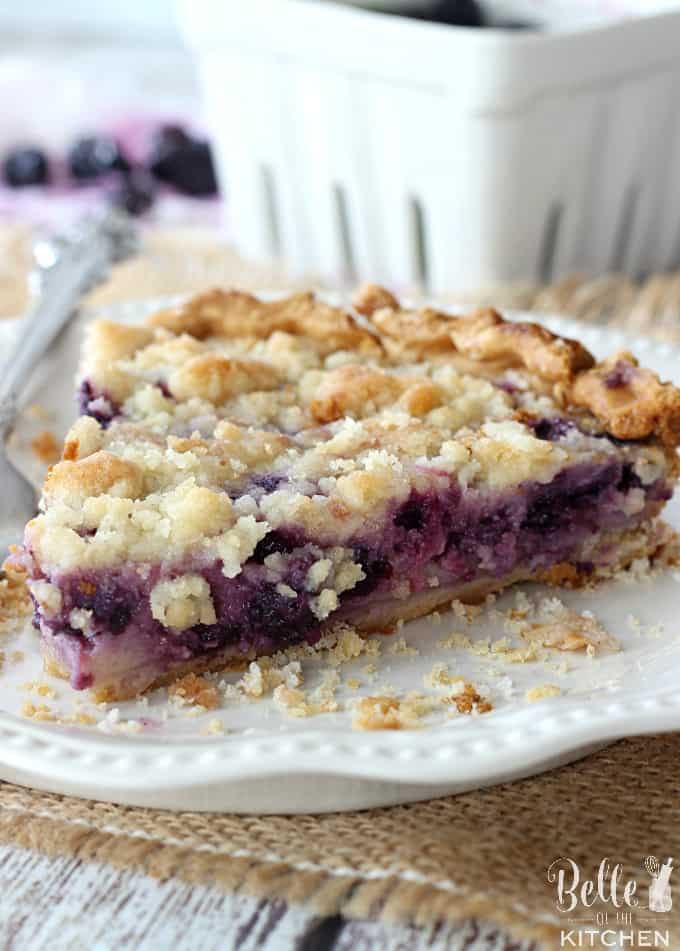 A close up of a piece of pie on a plate, with blueberries